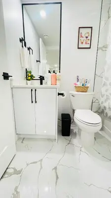 a white bathroom with a toilet and a mirror at Ivey Homes in Edmonton