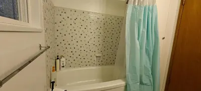 a bathroom with a tub and a shower curtain at Spacious Family Room with Shared Washroom in Vancouver