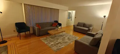 a living room with two couches and a table at Spacious Family Room with Shared Washroom in Vancouver
