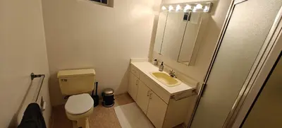 a bathroom with a toilet and a sink and a mirror at Spacious Family Room with Shared Washroom in Vancouver