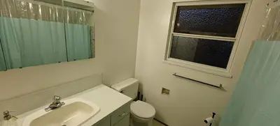 a bathroom with a sink and a toilet and a window at Spacious Family Room with Shared Washroom in Vancouver