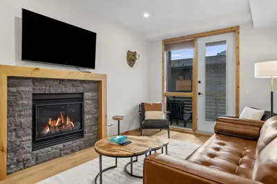 a living room with a fireplace with a flat screen tv at Creekside Cove in Spring Creek in Canmore