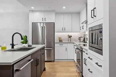 a kitchen with white cabinets and a stainless steel refrigerator at Creekside Cove in Spring Creek in Canmore