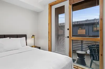 a bedroom with a bed and a balcony with a window at Creekside Cove in Spring Creek in Canmore