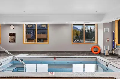 a large swimming pool in a building with windows at Creekside Cove in Spring Creek in Canmore