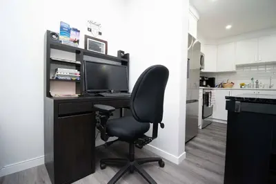 a desk with a monitor and a chair in a kitchen at Cozy Luxe Suites in Calgary