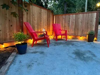 two red chairs and a table in front of a fence at Lake Trail Guesthouse in Victoria