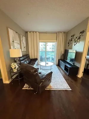 a living room with a leather couch and a television at Peaceful Condo for Short and Long Term Rental in Edmonton