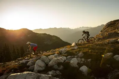 two people riding bikes on top of a mountain at 2BR in Symphony, Hot Tub, Gas Fireplace, Epic Village Location, Ski Shuttle in Whistler