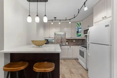 a kitchen with white cabinets and a counter with stools at 1BR and Sofabed in The Gables, Epic Village Location, Secure Parking, Forest Views in Whistler