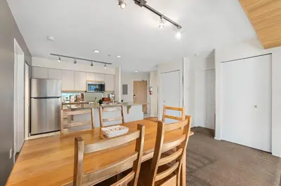 a kitchen and dining room with a wooden table and chairs at 2BR in Ironwood, Stunning Mountain Views, Shared Hot Tub and Pool, Fireplace, Parking in Whistler