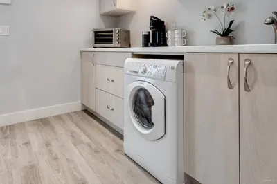 a kitchen with a washing machine in a kitchen at Spacious 1BR Suite Near Capilano Bridge & Trails in North Vancouver