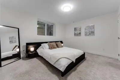 a white bedroom with a bed and a mirror at Modern 2Bed Suite Near Capilano Bridge & Trails in North Vancouver