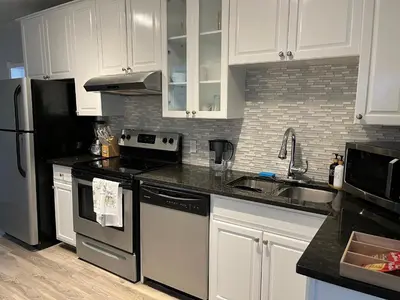 a kitchen with white cabinets and stainless steel appliances at Character Home near Downtown and 17th Avenue in Calgary