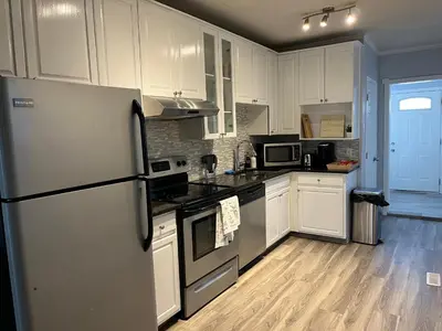 a kitchen with white cabinets and a refrigerator at Character Home near Downtown and 17th Avenue in Calgary