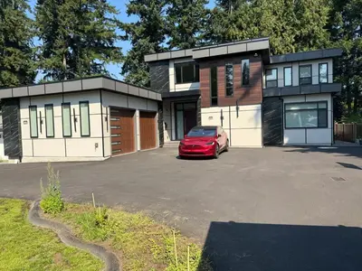a red car parked in front of a house at Peaceful 2BR Getaway with Fireplace & Parking Basement Suite in Abbotsford