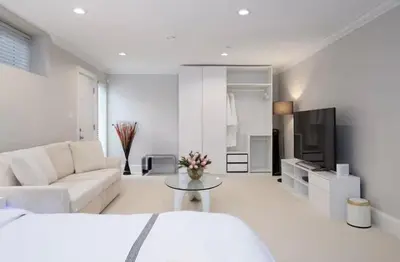 a white living room with a couch and a tv at Stylish Home in Van West Side Near YVR&DT in Vancouver