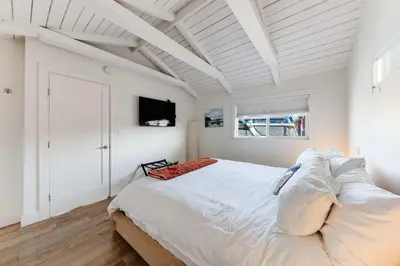 a white bedroom with a bed and a tv at Cozy modern floating home next to Lonsdale Quay in North Vancouver