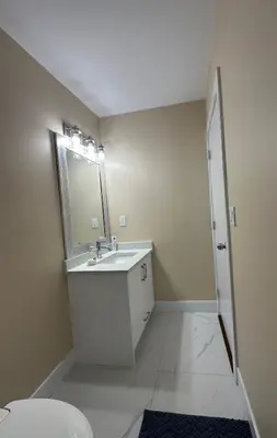 a white bathroom with a sink and a mirror at Cozy Ground-Floor Room with Private Bath and Separate Entry in Delta