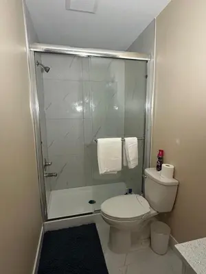 a bathroom with a toilet and a glass shower at Cozy Ground-Floor Room with Private Bath and Separate Entry in Delta