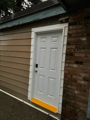 a garage with a white door on a brick building at Cozy Ground-Floor Room with Private Bath and Separate Entry in Delta
