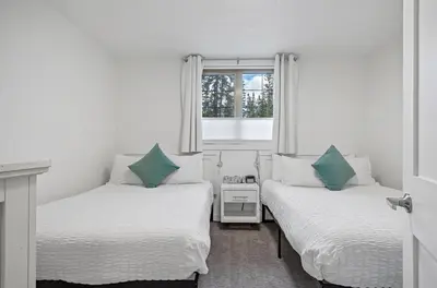 two beds in a room with a window at Marvellous Poolside Chalet - Pool & Hot Tub - Pets in Canmore