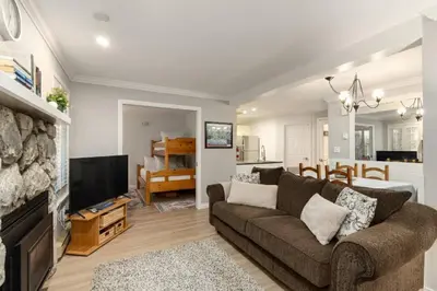 a living room with a couch and a tv and a kitchen at Ski-In/Out | Upper Village | Free Parking in Whistler