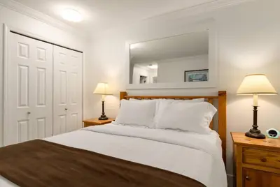 a bedroom with a bed with a mirror and two lamps at Ski-In/Out | Upper Village | Free Parking in Whistler