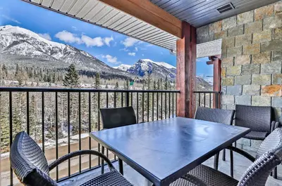 a table and chairs on a balcony with mountains at Fantastic Mountain View - Hot Tubs & Steam Room in Canmore