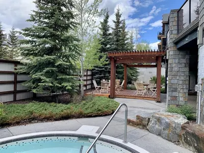 a backyard with a hot tub and a wooden pergola at Stunning Condo - Hot Tubs & Steam Room - Pets Ok in Canmore