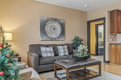 a living room with a couch and a christmas tree at Stunning Condo - Hot Tubs & Steam Room - Pets Ok in Canmore