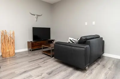 a living room with a black leather couch and a television at Corporate Stays Village on 105 1 Bedroom in Edmonton
