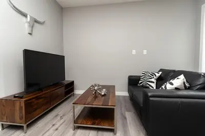 a living room with a black couch and a coffee table at Corporate Stays Village on 105 1 Bedroom in Edmonton