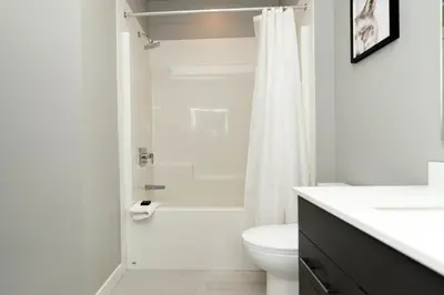 a white bathroom with a toilet and a shower at Corporate Stays Village on 105 1 Bedroom in Edmonton