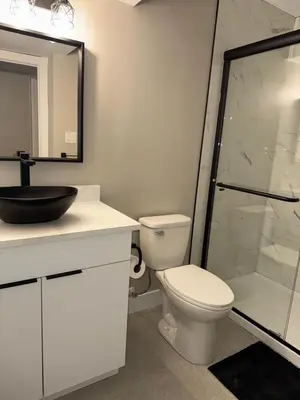 a bathroom with a toilet and a glass shower at NorthEdge Suites in Edmonton