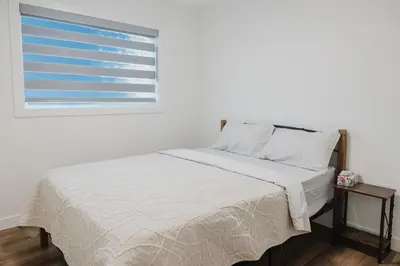 a bed in a white room with a window at Brown Family Vacation Home in Leduc