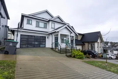 a large white house with a driveway at Bright & Modern Surrey Basement Suite with Queen Beds & Parking in Surrey