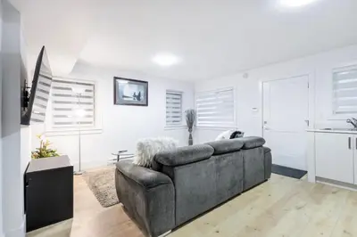 a living room with a couch and a kitchen at Bright & Modern Surrey Basement Suite with Queen Beds & Parking in Surrey