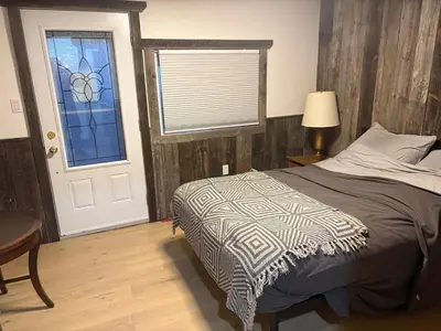 a bedroom with a bed and a window and a door at maison de la Ferme in Bélanger