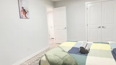 a white bedroom with a bed and a picture on the wall at Zillion’s Bliss - Basement Suite in Calgary