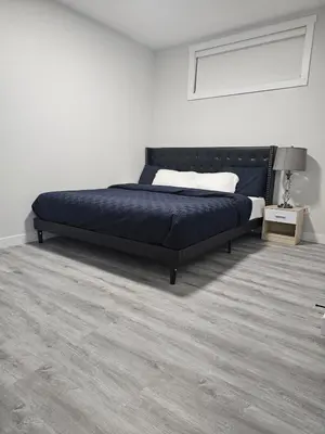a bedroom with a bed in a white room at Cozy on 516 in Airdrie