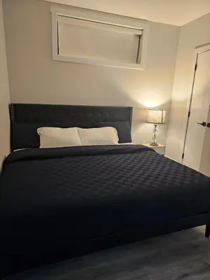 a black bed in a room with a lamp at Cozy on 516 in Airdrie