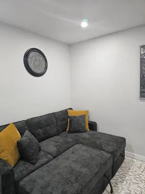 a living room with a couch and a clock on the wall at Cozy on 516 in Airdrie
