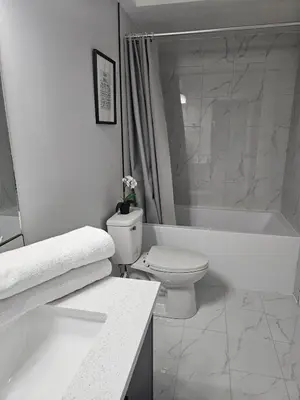 a white bathroom with a toilet and a bath tub at Cozy on 516 in Airdrie
