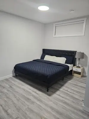 a bedroom with a black bed in a white room at Cozy on 516 in Airdrie