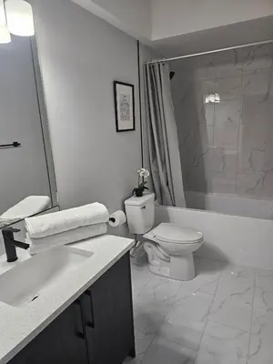 a white bathroom with a toilet and a sink at Cozy on 516 in Airdrie