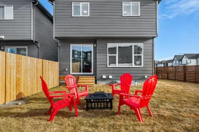 four red chairs and a table in front of a house at The Herron Rise Retreat in Calgary