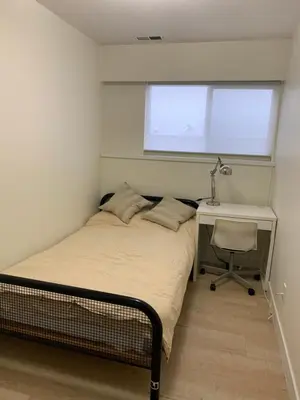 a bedroom with a bed and a desk and a window at Modern 2-Bedroom suite in Burnaby