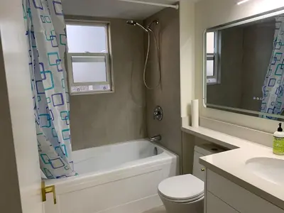 a bathroom with a tub and a toilet and a sink at Modern 2-Bedroom suite in Burnaby