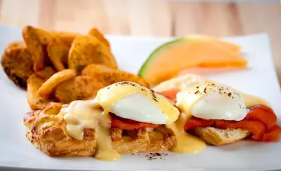 a plate of food with waffles and french fries at Applause Hotel Calgary Airport by CLIQUE in Calgary